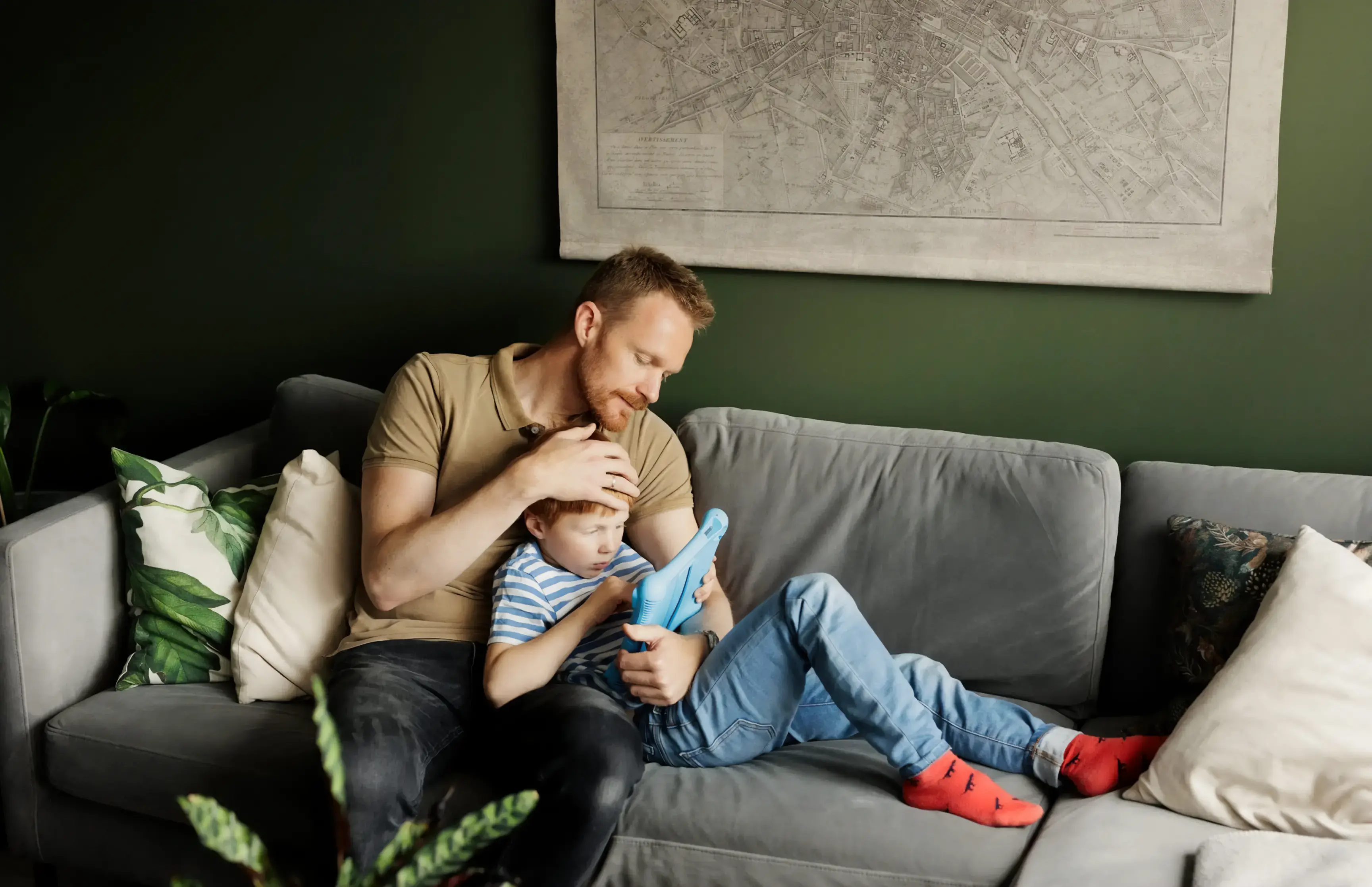 En mann med et barn som sitter i sofaen